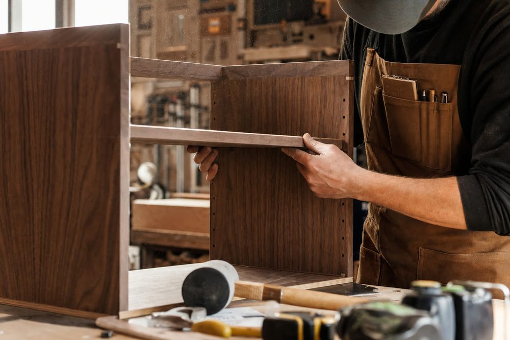 Craftsman assembling a frameless walnut cabinet in the Knack Woodcraft shop